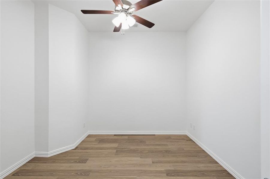 Room featuring wood-finish flooring, white baseboards, and a ceiling fan with light fixture