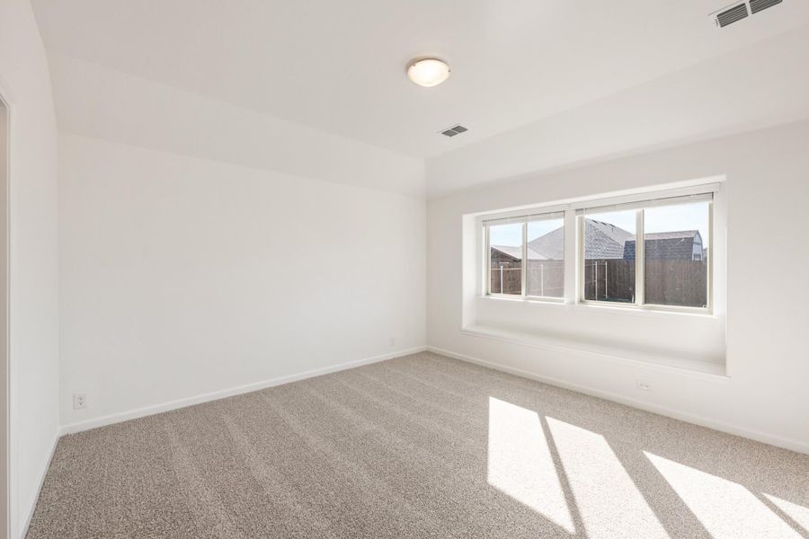 Empty bedroom with white walls, beige carpet, and a large window with natural light