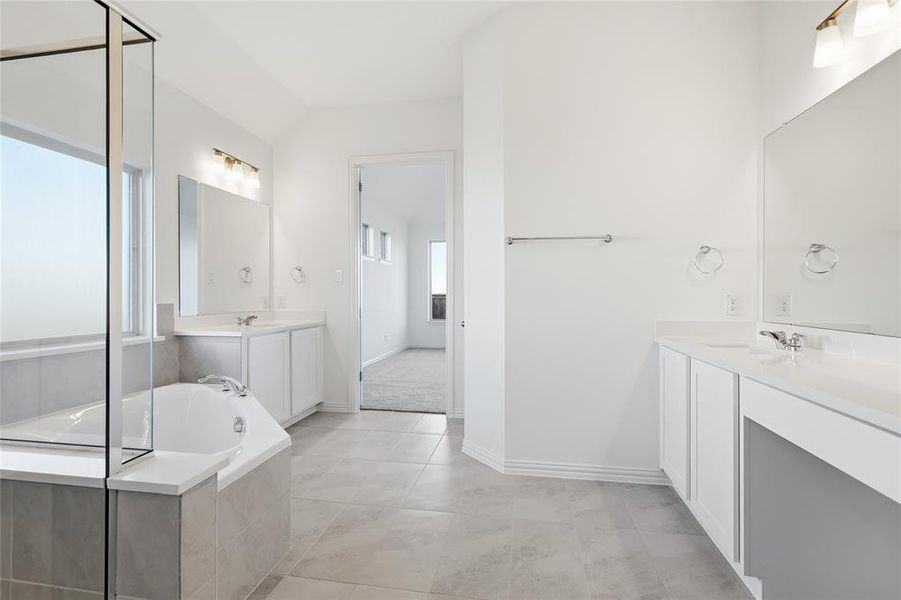 Spacious bathroom featuring dual vanities with white cabinetry, light countertops, and individual mirrors