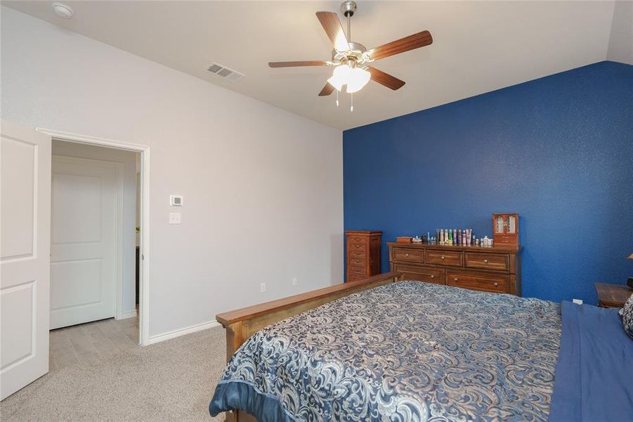 Bedroom with ceiling fan, light colored carpet, and vaulted ceiling