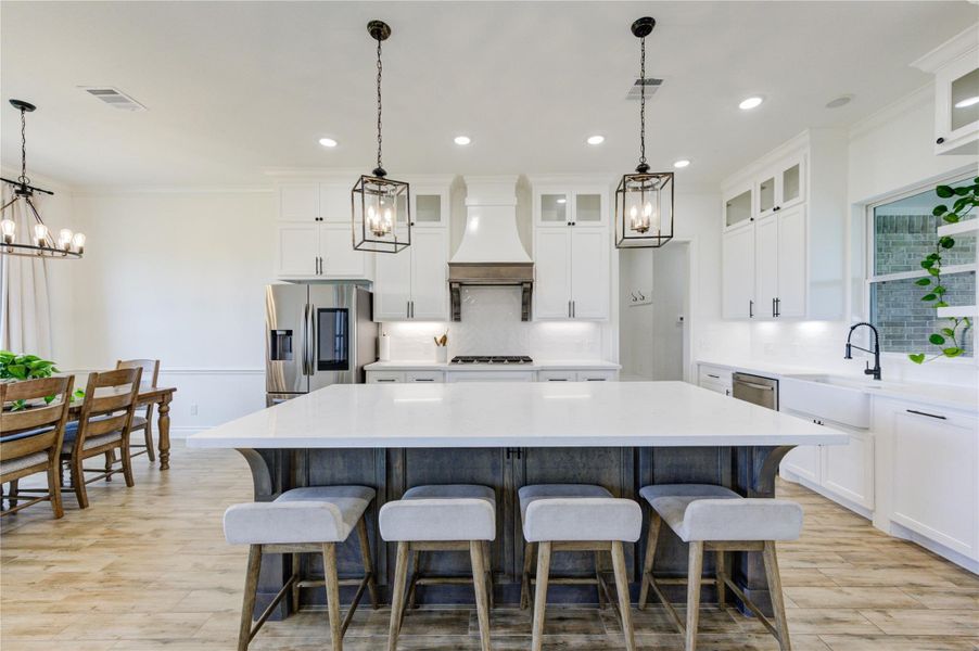 Gourmet kitchen with oversized island, quartz counters, and pendant lighting