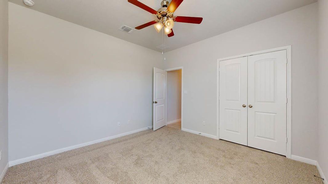 Unfurnished bedroom featuring light colored carpet, a ceiling fan, and a closet
