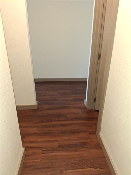 Hallway featuring dark wood-style floors and a textured wall Hallway featuring dark wood-style floors and a textured wall