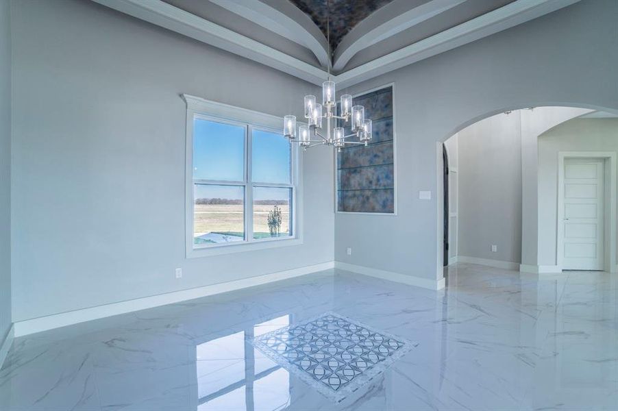 Unfurnished dining area with light marble finish flooring, a chandelier, and arched walkways