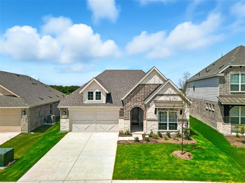 View of front of house featuring stone siding, a front lawn, a shingled roof, concrete driveway, and board and batten siding View of front of house featuring stone siding, a front lawn, a shingled roof, concrete driveway, and board and batten siding