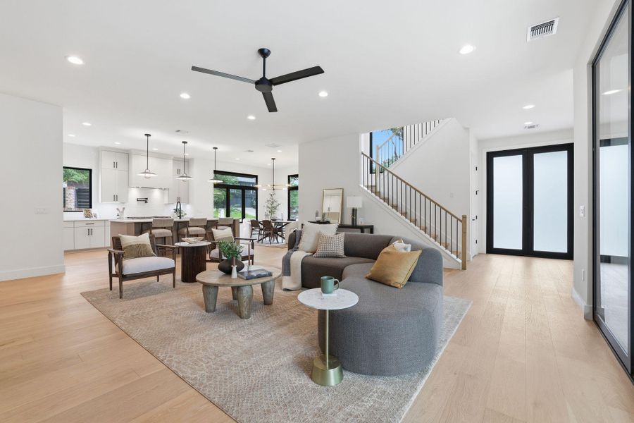 Spacious living area featuring light wood-finish flooring, recessed lighting, and a contemporary ceiling fan