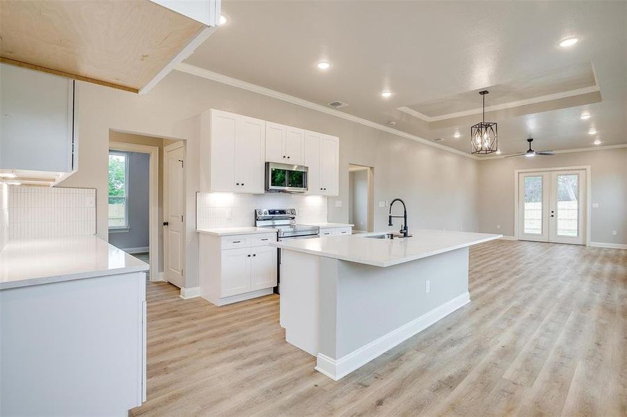 Kitchen with white cabinets, a sink, light wood finished floors, plenty of natural light, and stainless steel appliances Kitchen with white cabinets, a sink, light wood finished floors, plenty of natural light, and stainless steel appliances