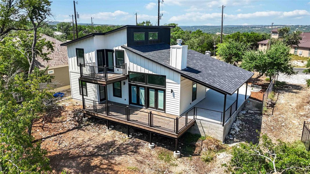 Back of property featuring roof with shingles, a chimney, a wooden deck, and a balcony Back of property featuring roof with shingles, a chimney, a wooden deck, and a balcony