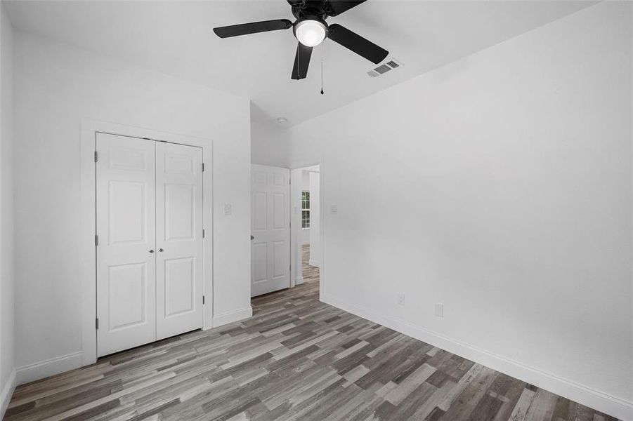 Unfurnished bedroom with light wood-type flooring, a ceiling fan, and a closet