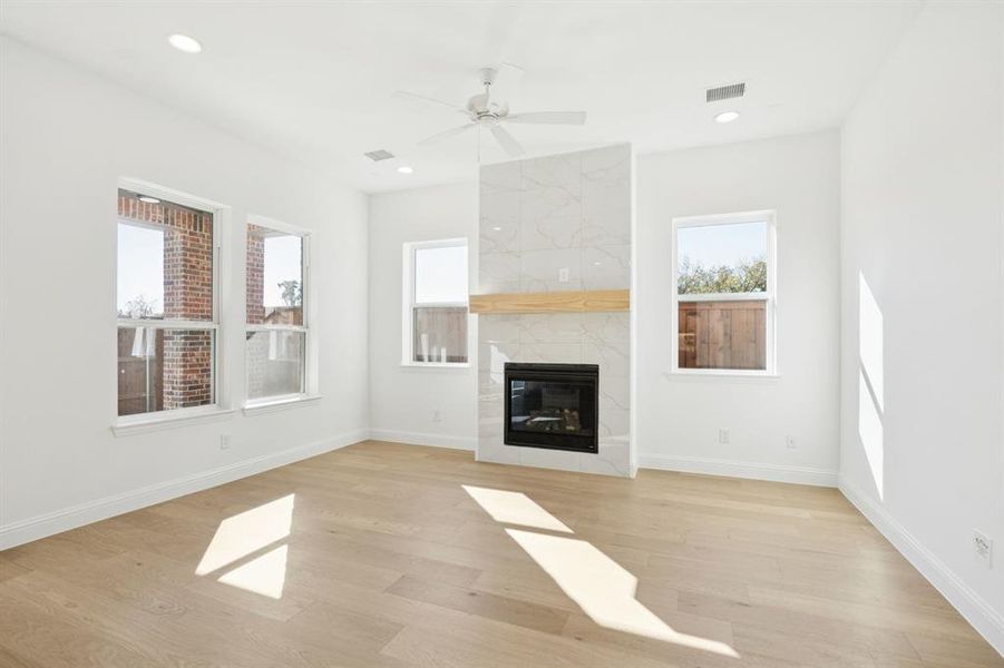 Living room featuring light wood-type flooring, a fireplace, ceiling fan, and recessed lighting
