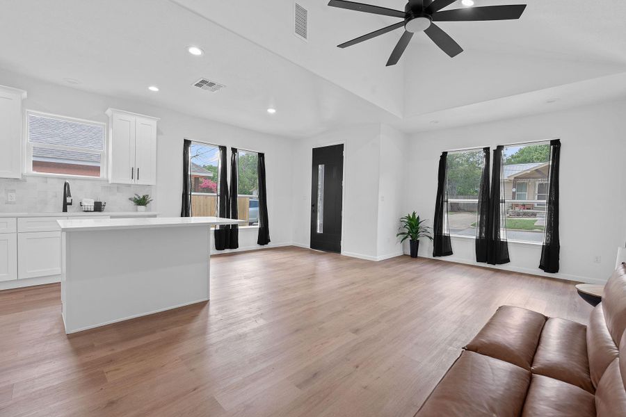 Unfurnished living room featuring recessed lighting, healthy amount of natural light, ceiling fan, light wood-type flooring, and vaulted ceiling