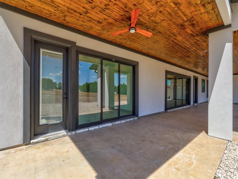 Rich wood plank ceilings and smooth concrete flooring define this sheltered outdoor transition space.