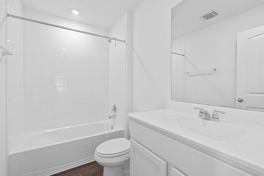 Bathroom with washtub / shower combination, vanity, and dark wood-style floors Bathroom with washtub / shower combination, vanity, and dark wood-style floors