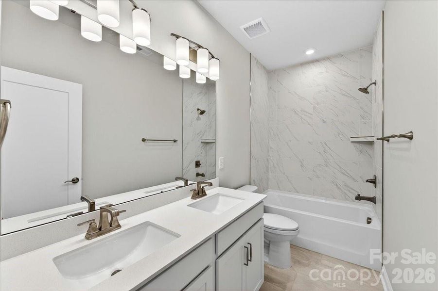 Dual vanity secondary bathroom with tile above the tub Dual vanity secondary bathroom with tile above the tub