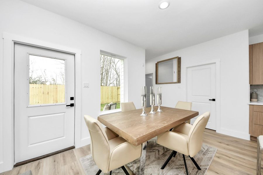 Bright dining area with modern design, featuring a wooden table and beige chairs. The space has a door and window providing natural light, with light wood flooring and white walls for a contemporary feel. Bright dining area with modern design, featuring a wooden table and beige chairs. The space has a door and window providing natural light, with light wood flooring and white walls for a contemporary feel.