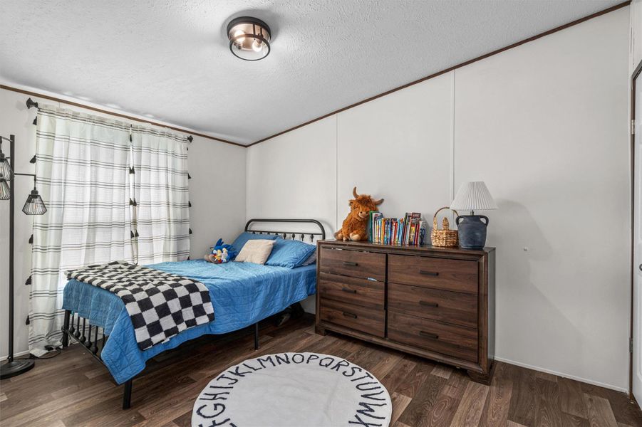 Bedroom featuring a textured ceiling and dark wood finished floors