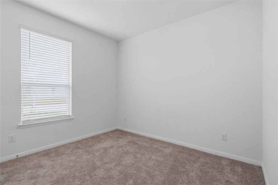 This secondary bedroom offers comfort and style with plush carpeting, neutral paint tones, a large window with blinds, and a generously sized closet.