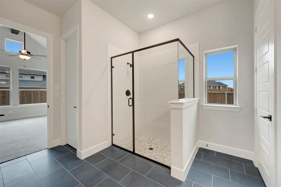 Bathroom with a shower stall, dark tile patterned flooring, healthy amount of natural light, ceiling fan, and recessed lighting