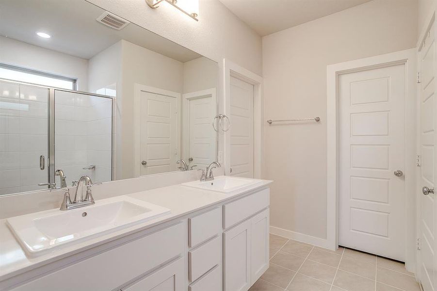 Full bath featuring light tile patterned floors, double vanity, and a shower stall Full bath featuring light tile patterned floors, double vanity, and a shower stall