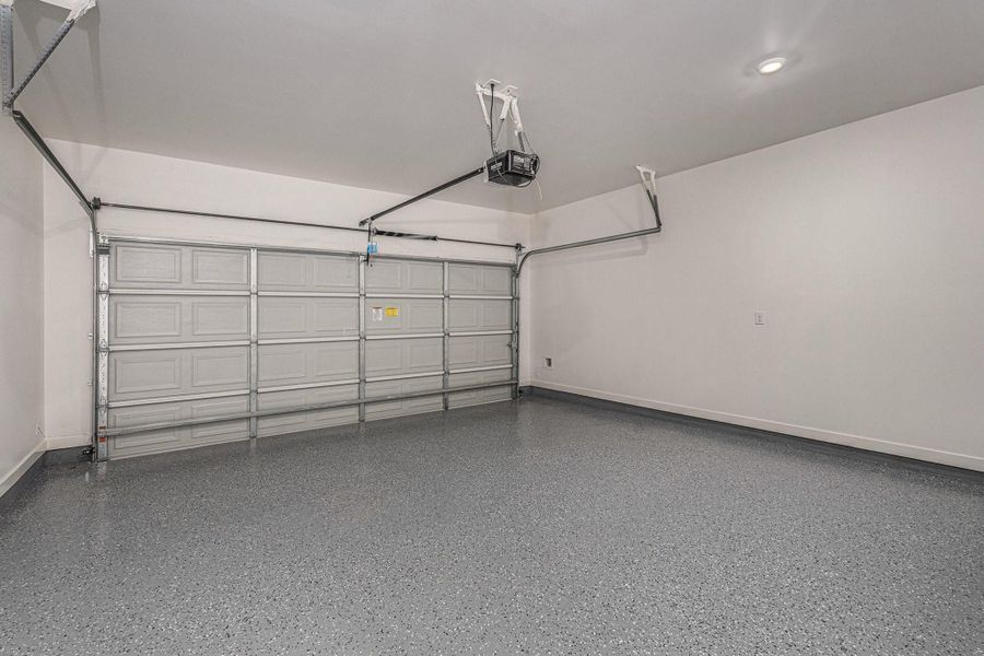 This spacious, clean garage features a polished floor, a double-door with an automatic opener, and ample overhead lighting. Ideal for storage or parking.