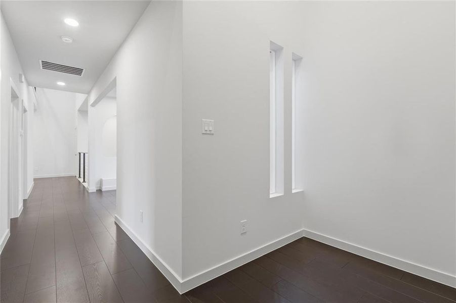 Hallway featuring dark wood-finish flooring, recessed lighting, and white baseboards