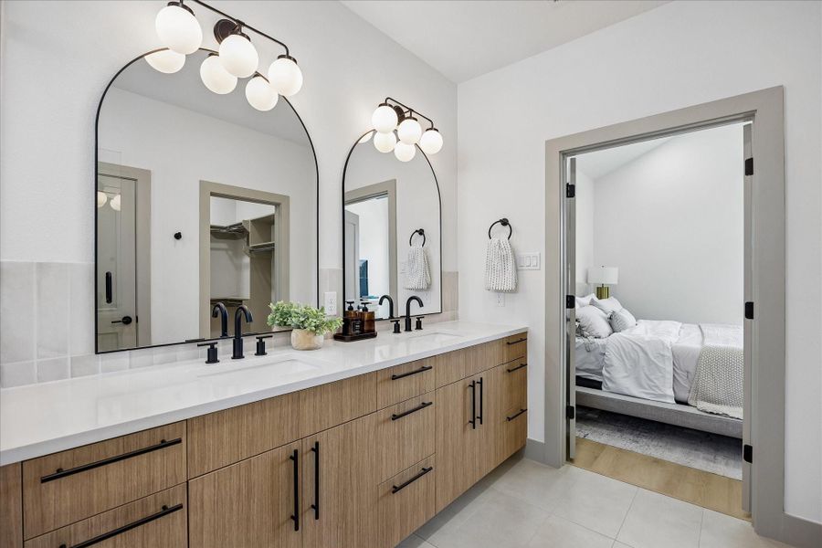 Dual vanities, warm wood cabinetry, quartz countertops, and oversized arched mirrors create a refined everyday routine. Dual vanities, warm wood cabinetry, quartz countertops, and oversized arched mirrors create a refined everyday routine.