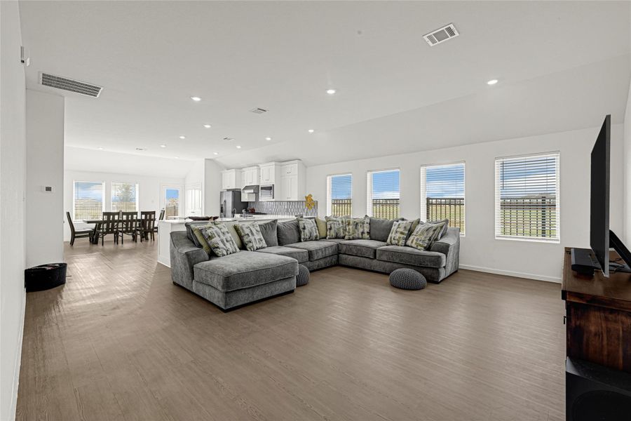 This spacious open-plan living area features an abundant of natural lighting. The room seamlessly flows into a modern kitchen with white cabinetry and stainless-steel appliances, and a dining area with ample seating. Perfect for entertaining and family gatherings. This spacious open-plan living area features an abundant of natural lighting. The room seamlessly flows into a modern kitchen with white cabinetry and stainless-steel appliances, and a dining area with ample seating. Perfect for entertaining and family gatherings.