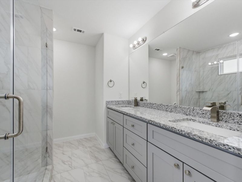The primary en-suite is thoughtfully finished with dual sinks, a sleek glass-enclosed shower, and a spacious walk-in closet designed for everyday comfort.