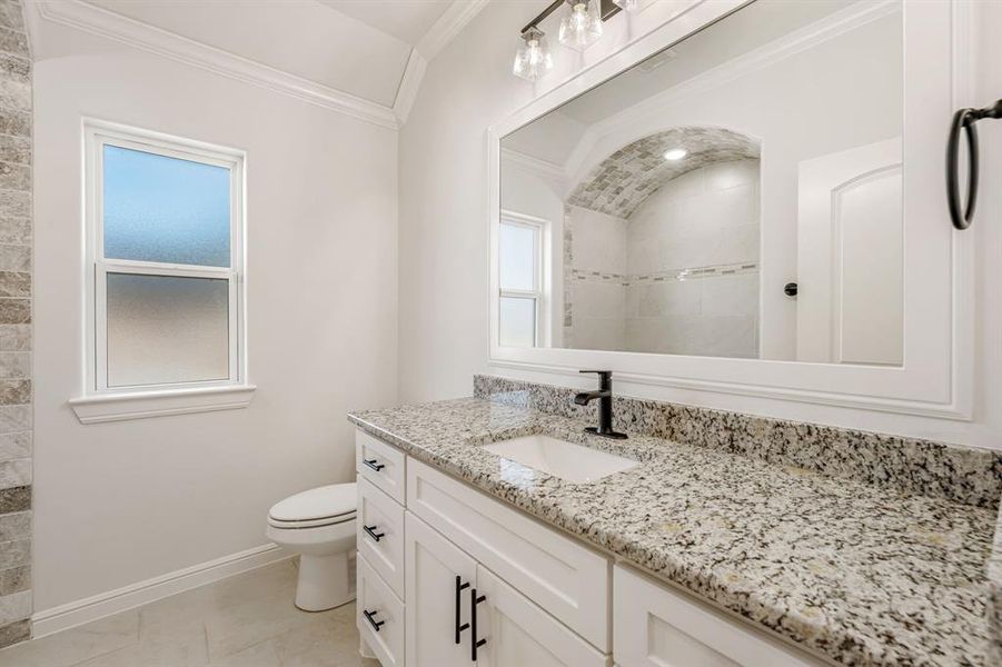 Bathroom with tile patterned floors, toilet, vanity, and crown molding