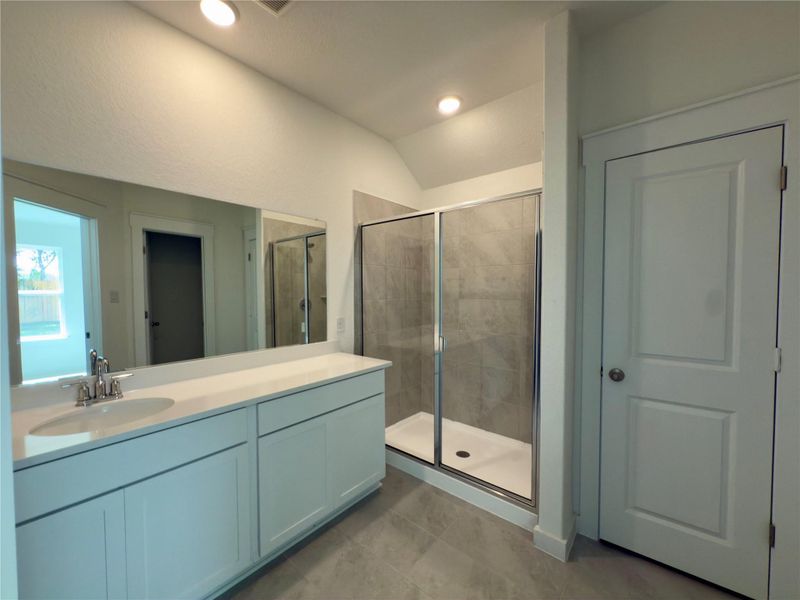 Full bath with a shower stall, vanity, vaulted ceiling, light tile patterned flooring, and recessed lighting Full bath with a shower stall, vanity, vaulted ceiling, light tile patterned flooring, and recessed lighting