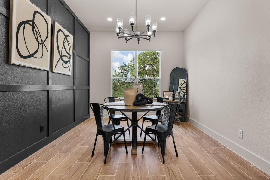 A well-lit dining area features a prominent window overlooking verdant foliage, complementing the rich wood flooring.