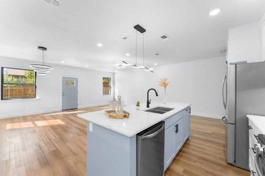 Kitchen with open floor plan, hanging light fixtures, stainless steel appliances, light wood-type flooring, and recessed lighting Kitchen with open floor plan, hanging light fixtures, stainless steel appliances, light wood-type flooring, and recessed lighting
