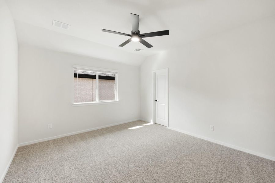 Empty bedroom with vaulted ceiling, black ceiling fan, and beige carpet