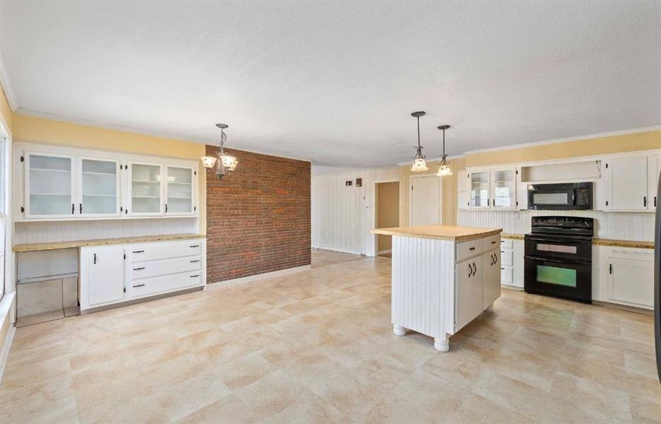 Kitchen featuring glass insert cabinets, white cabinets, light countertops, black appliances, and decorative light fixtures