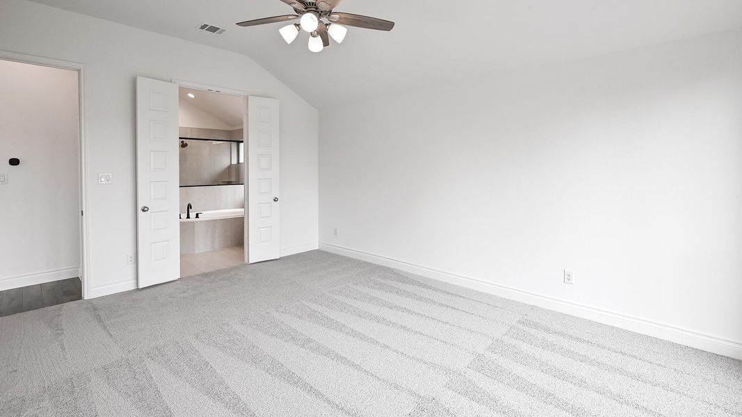 Unfurnished bedroom with carpet flooring, lofted ceiling, baseboards, ceiling fan, and ensuite bathroom Unfurnished bedroom with carpet flooring, lofted ceiling, baseboards, ceiling fan, and ensuite bathroom