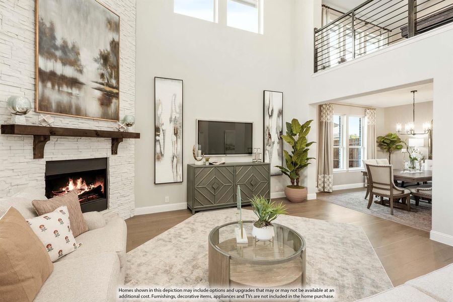 Living room with two-story ceiling, stone fireplace, hardwood floors, and open view to dining room