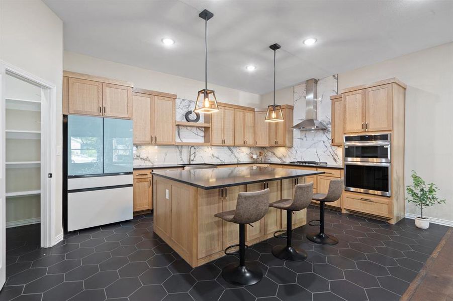 Kitchen featuring light brown cabinets, stainless steel appliances, a kitchen bar, pendant lighting, and recessed lighting Kitchen featuring light brown cabinets, stainless steel appliances, a kitchen bar, pendant lighting, and recessed lighting