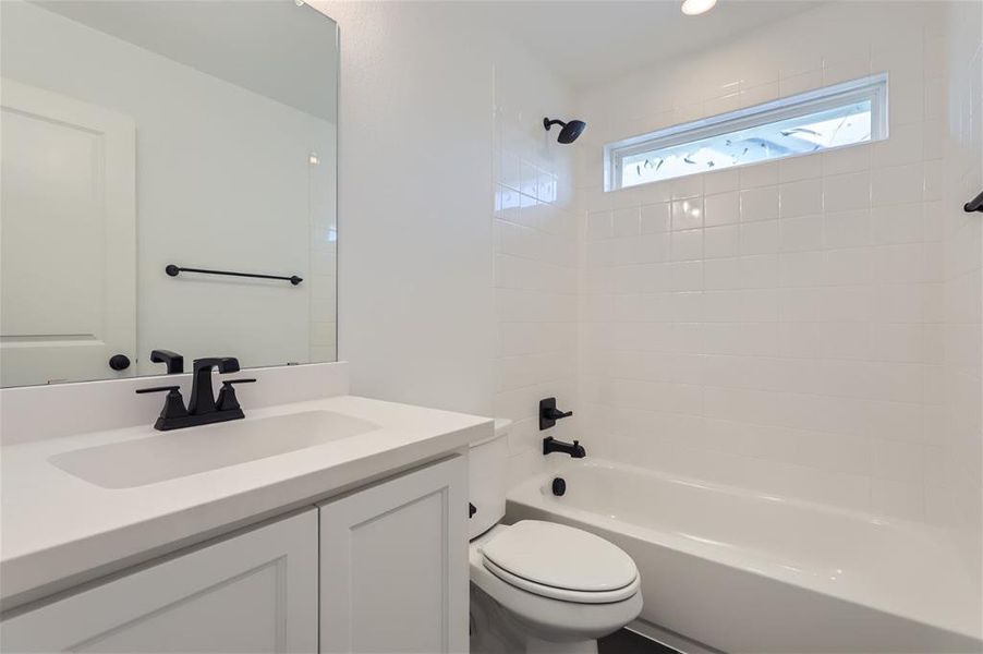 Full bathroom with tiled shower / bath combo, toilet, and vanity