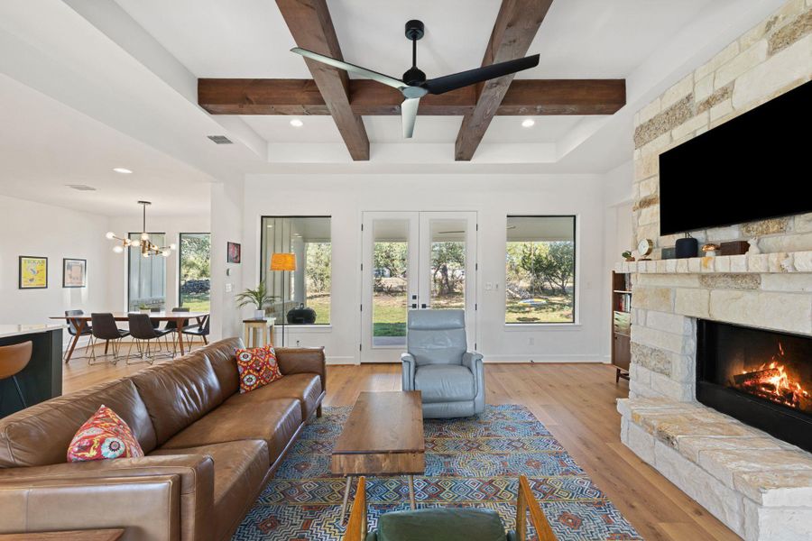 Living area with light wood-style floors, beamed ceiling, a fireplace, recessed lighting, and french doors