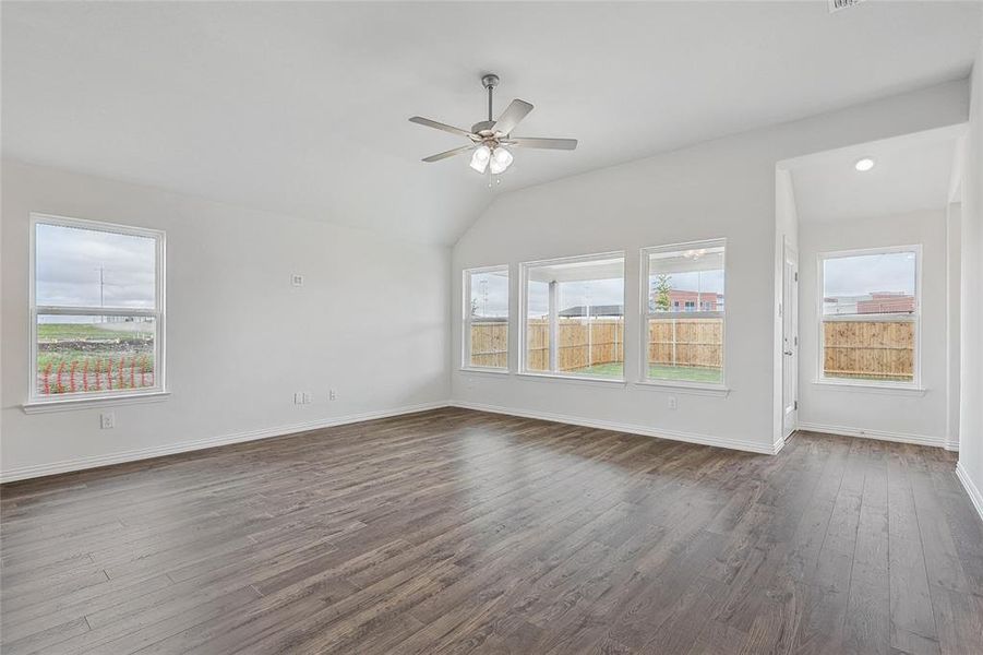 Unfurnished living room featuring lofted ceiling, dark hardwood / wood-style floors, and ceiling fan