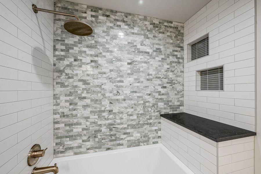 Statement tile wall in soft marble tones with coordinating niche and brass fixtures for a polished finish. Statement tile wall in soft marble tones with coordinating niche and brass fixtures for a polished finish.