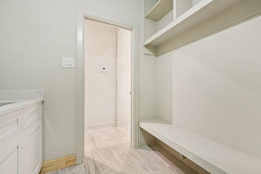 A different view of the laundry room  with built-in bench, and shelving.