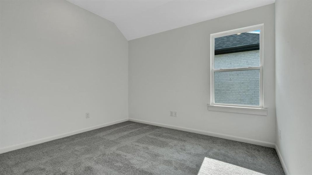 Carpeted empty room featuring vaulted ceiling