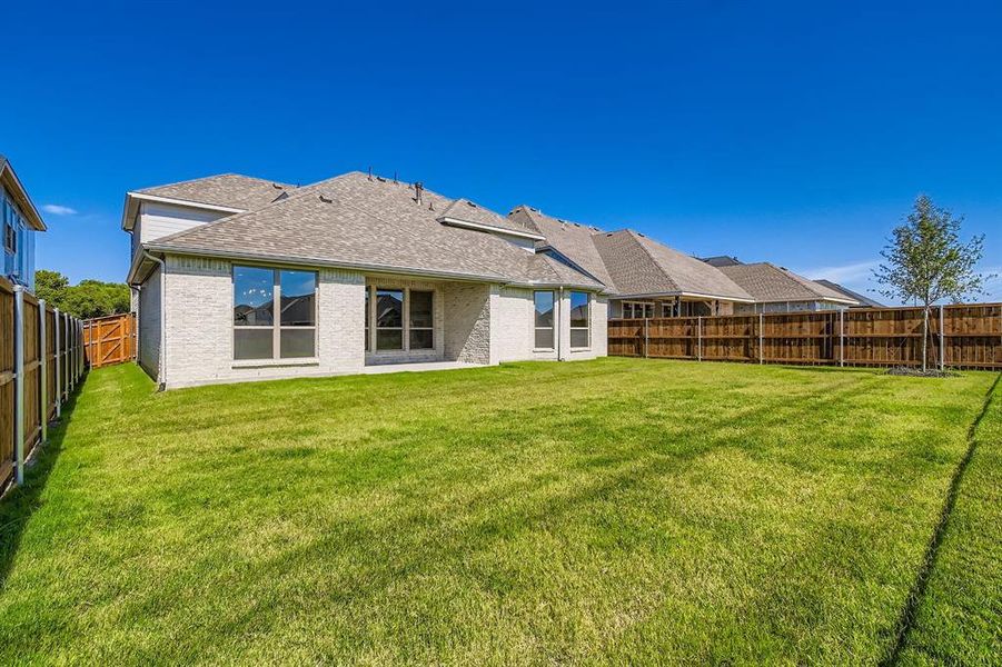 Back of house featuring roof with shingles, a fenced backyard, and brick siding