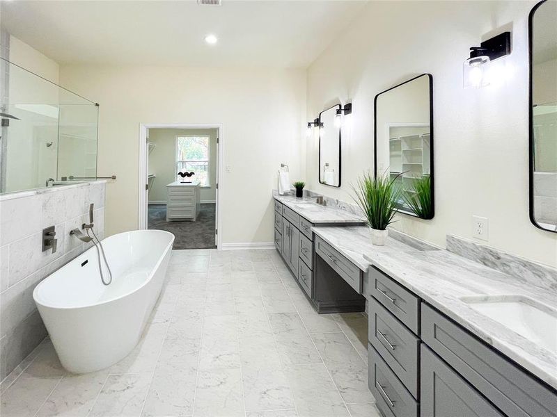 Bathroom with dual vanity, tile flooring, a bath to relax in, and tile walls