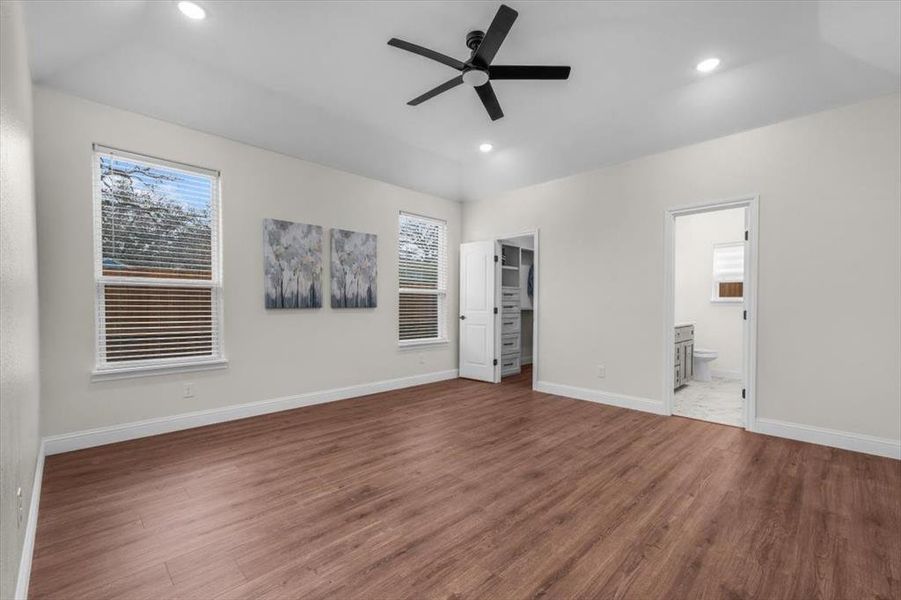 Unfurnished bedroom with hardwood / wood-style flooring, ceiling fan, connected bathroom, and a spacious closet