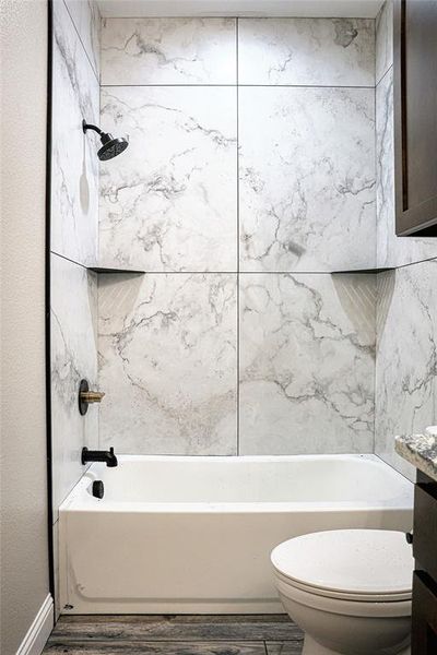 Secondary bathroom featuring vanity, tiled shower / bath, and toilet