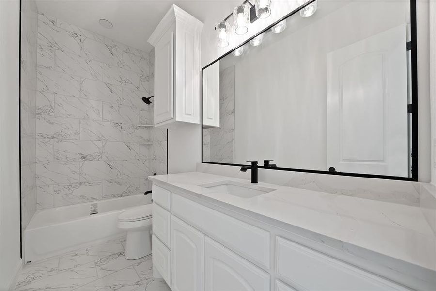 Secondary bathroom featuring light marble finish flooring, bathtub / shower combination, and vanity