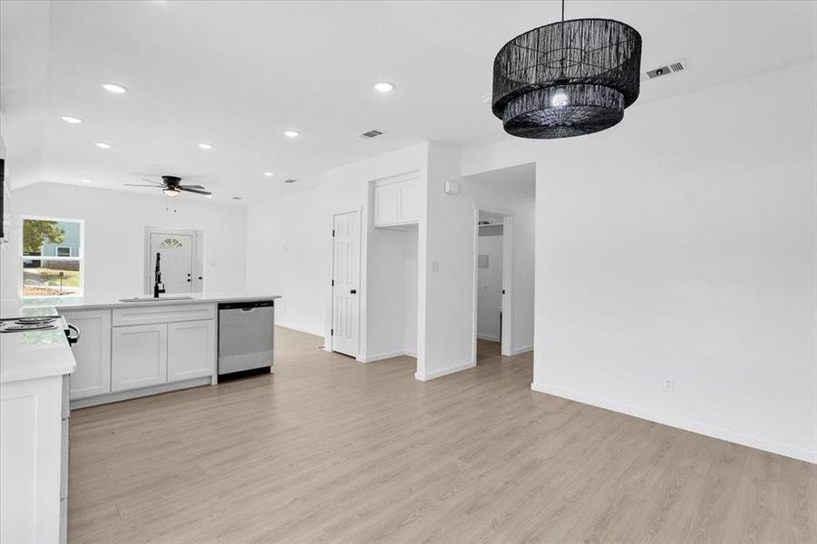 Kitchen featuring stainless steel dishwasher, sink, light wood-type flooring, white cabinets, and ceiling fan