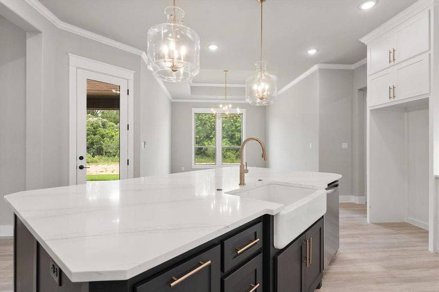 Kitchen island featuring a white apron-front sink, a gold-finish faucet, and a light-toned countertop